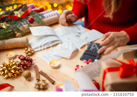 Close up of girl looking through checks of christmas expenses. Checks from stores for presents and decorations bought for christmas 131810750