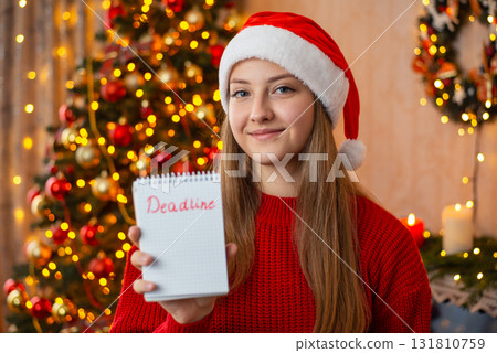 Girl with Deadline notes in decorated living room. Christmas celebration, doing tasks before New Year 131810759