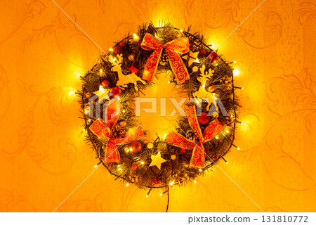 Close up shot of Christmas wreath on the wall. Bright Christmas wreath with bows in lights on the wall Close up shot of Christmas wreath on the wall. Bright Christmas wreath with bows in lights on the wall 131810772