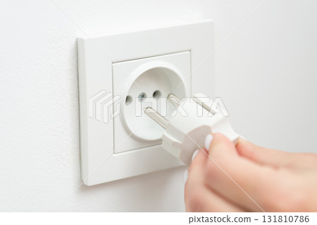 Inserting the electrical plug into outlet of the wall, white colour, close up. Consumption of electricity, modern technologies concept Inserting the electrical plug into outlet of the wall, white colour, close up. Consumption of electricity, modern technologies concept 131810786