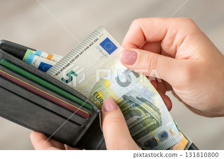 Euro banknote in wallet in hands of a woman, close up. Buying things and paying for them, exchange, small money Euro banknote in wallet in hands of a woman, close up. Buying things and paying for them, exchange, small money 131810800