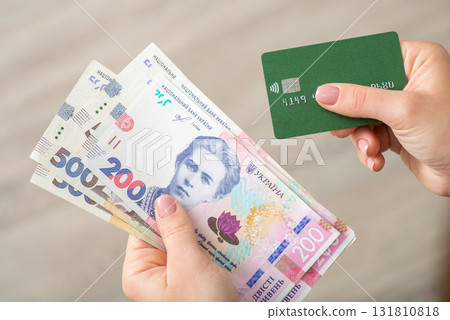 Ukrainian hryvnia 200 banknotes and credit card in female hands. Banking, paying, finances and economy concept Ukrainian hryvnia 200 banknotes and credit card in female hands. Banking, paying, finances and economy concept 131810818