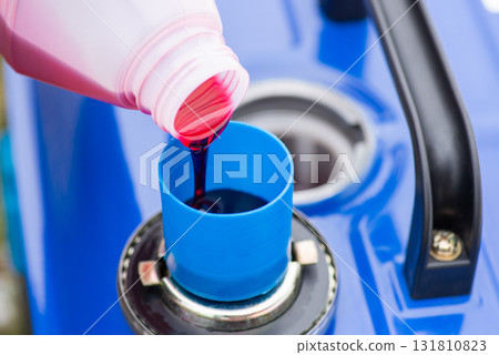 Pouring oil to measuring cup to add it to fuel tank. Refilling two-stroke electric generator concept Pouring oil to measuring cup to add it to fuel tank. Refilling two-stroke electric generator concept 131810823