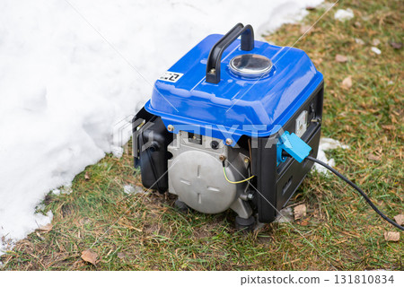 Working electric generator outdoors on lawn. Small autonomous gasoline generator supplying private house with energy during blackout Working electric generator outdoors on lawn. Small autonomous gasoline generator supplying private house with energy during blackout 131810834