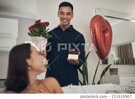 Surprise, love and man with a gift and roses for his wife for valentines day, romance or anniversary. Happy, romantic and husband with present and bouquet of flowers for his woman in the living room. Surprise, love and man with a gift and roses for his wife for valentines day, romance or anniversary. Happy, romantic and husband with present and bouquet of flowers for his woman in the living room. 131810907