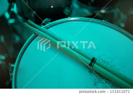 Top view of sticks on drums instrument in music studio, production or live band in neon green light. Background closeup of drum kit of musician, concert and sound performance to record at talent show Top view of sticks on drums instrument in music studio, production or live band in neon green light. Background closeup of drum kit of musician, concert and sound performance to record at talent show 131811071