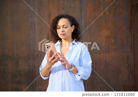 Portrait Of A Woman Using Smartphone Outdoors In A Casual Blue Shirt Portrait Of A Woman Using Smartphone Outdoors In A Casual Blue Shirt 131811080