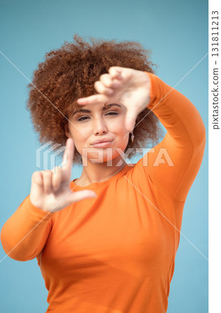 Hands, frame and portrait of black woman on blue background for profile picture. Face, female and finger framing for perspective, selfie and vision of aesthetic focus, idea and photography in studio Hands, frame and portrait of black woman on blue background for profile picture. Face, female and finger framing for perspective, selfie and vision of aesthetic focus, idea and photography in studio 131811213