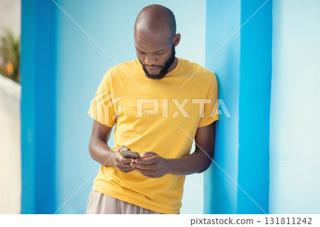 Thinking black man, phone or typing on blue background on social media, internet app or reading news blog. Fashion clothes, person or student on mobile technology with fashion clothes ideas or vision 131811242