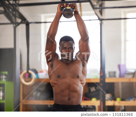 Black man, bodybuilder and kettlebell for fitness in gym, arm muscle training, portrait and weightlifting exercise. Biceps, strong and bodybuilding, focus and serious with commitment to workout 131811368