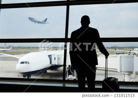 Airport, travel and silhouette business man watch plane fly, flight booking or transportation for world trip. Suitcase luggage, airport departure and back of person on holiday, vacation or journey Airport, travel and silhouette business man watch plane fly, flight booking or transportation for world trip. Suitcase luggage, airport departure and back of person on holiday, vacation or journey 131811513