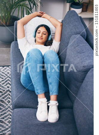 Music, relax and lying with a woman in her home, listening to the radio while on a sofa in the living room. Peace, wellness or headphones with an attractive young female streaming audio in a house Music, relax and lying with a woman in her home, listening to the radio while on a sofa in the living room. Peace, wellness or headphones with an attractive young female streaming audio in a house 131811803