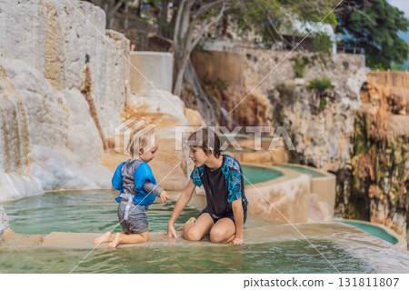 Teenage boy and his toddler brother bathing in the hot springs of Grutas Tolantongo, Mexico, enjoying family bonding, wellness, and outdoor adventure concept Teenage boy and his toddler brother bathing in the hot springs of Grutas Tolantongo, Mexico, enjoying family bonding, wellness, and outdoor adventure concept 131811807