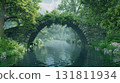 Ancient stone bridge covered in vines arches over a tranquil forest river with lush green foliage 131811934