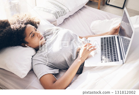 Music earphones, woman and laptop in bed in bedroom for social media or internet browsing in the morning. Technology, relax or black female with computer for streaming podcast, audio or radio in home 131812002