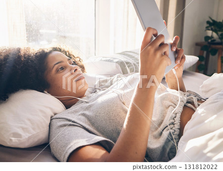 Music earphones, black woman and tablet in bed in bedroom for social media, texting or internet browsing in the morning. Technology, relax and female with touchscreen for streaming podcast or radio. Music earphones, black woman and tablet in bed in bedroom for social media, texting or internet browsing in the morning. Technology, relax and female with touchscreen for streaming podcast or radio. 131812022
