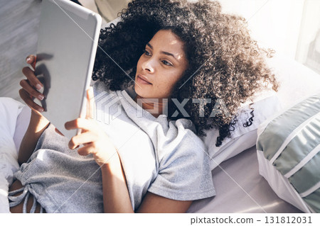 Tablet, black woman and relax in bed in bedroom for social media, texting or internet browsing in the morning. Technology, home and female with digital touchscreen for web scrolling after waking up. 131812031