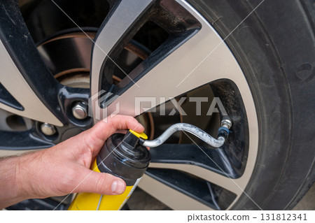 Selective focus on chemical additive sprayed from a can into a tire to fix a flat Selective focus on chemical additive sprayed from a can into a tire to fix a flat 131812341