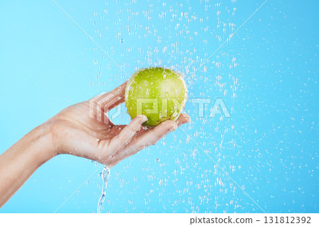 Water drops, apple cleaning and hands with fruit for wellness, healthcare and self care. Healthy food, green and natural skincare with a hand holding health snack for diet in blue background studio Water drops, apple cleaning and hands with fruit for wellness, healthcare and self care. Healthy food, green and natural skincare with a hand holding health snack for diet in blue background studio 131812392