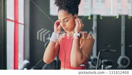 Woman, gym and earphones for music, thinking and listening for inspiration to workout for wellness. African girl, audio streaming subscription and hearing for exercise, training or fitness with sound Woman, gym and earphones for music, thinking and listening for inspiration to workout for wellness. African girl, audio streaming subscription and hearing for exercise, training or fitness with sound 131812408