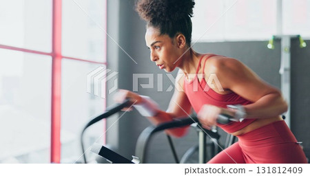 Woman, cycling and fitness at gym in cardio workout, exercise or indoor training for weight lose. Serious and active female person or athlete on bicycle machine for sports motivation or performance 131812409
