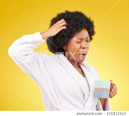 Coffee, yawning and tired black woman in studio, waking up in the morning or sleepy isolated on a yellow background. Exhausted, insomnia and female scratching head with tea or caffeine in bathrobe. 131812422