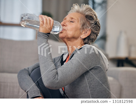 Drinking, water and fitness with a senior woman in her home for wellness, hydration or retirement. Exercise, drink or thirsty with a mature female training in a house during a workout to stay active 131812598