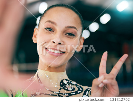 Selfie, peace and competition with a black woman gymnast in a gym posing for a picture while training alone. Portrait, hand sign and gymnastics with a female athlete in a studio for fitness or exerci Selfie, peace and competition with a black woman gymnast in a gym posing for a picture while training alone. Portrait, hand sign and gymnastics with a female athlete in a studio for fitness or exerci 131812702