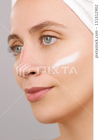 Young Caucasian woman applying make-up foundation. Putting face cream strip. Female portrait. Skincare ads concept. Sunscreen, morning beauty routine, facial moisturizer. Pretty lady. Gray background Young Caucasian woman applying make-up foundation. Putting face cream strip. Female portrait. Skincare ads concept. Sunscreen, morning beauty routine, facial moisturizer. Pretty lady. Gray background 131812902