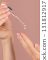 Vertical close-up of female hands on isolated pink background holding dropper, anti-aging facial serum, booster dripping on palm. Skincare, moisturizing, vitamin c, face lifting, anti-acne advertising 131812917
