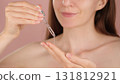 Young woman holding a dropper with serum for face. Macro view pink background. Dermatology, cosmetics, spa ads. Liquid collagen skincare product, beauty concept. Facial oil fall from a glass pipette  131812921