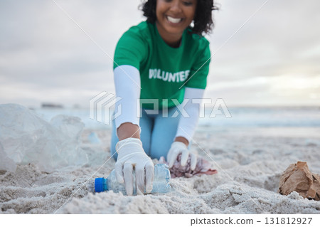 Hand, bottle and a volunteer woman on the beach for community, charity or activism during a clean up. Cleaning, environment and plastic with a female picking up plastic litter or polution on a coast 131812927