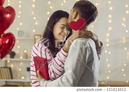 Happy man holding red red present box in his hand and congratulating pretty woman on holiday. 131813012