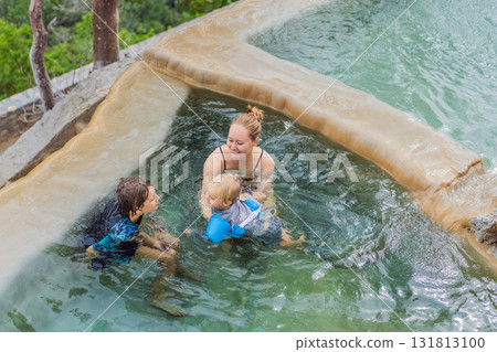 Mother with her toddler and teenage son bathing in the hot springs of Grutas Tolantongo, Mexico, enjoying family bonding, wellness, and outdoor adventure concept. 131813100
