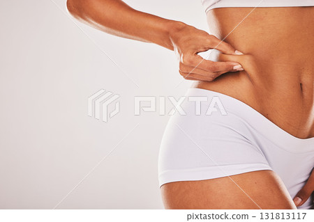 Fat, weight and woman touching her stomach isolated on a grey studio background with mockup space. Skin, cellulite and hands of a model feeling her body for insecurity, health and tummy tuck Fat, weight and woman touching her stomach isolated on a grey studio background with mockup space. Skin, cellulite and hands of a model feeling her body for insecurity, health and tummy tuck 131813117