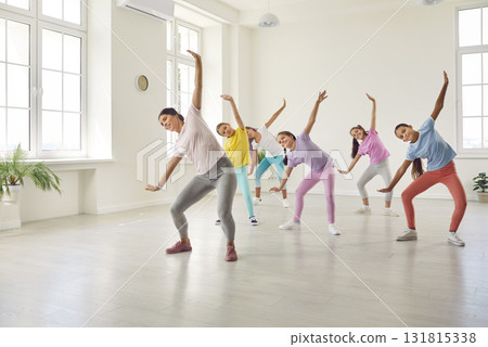Group of children in sportswear having a fitness dance workout with a woman trainer Group of children in sportswear having a fitness dance workout with a woman trainer 131815338