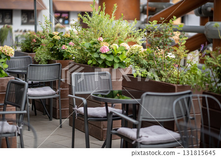 Modern european style empty street cafe with lovely natural flowers near tables in sunny day. Modern european style empty street cafe with lovely natural flowers near tables in sunny day. 131815645
