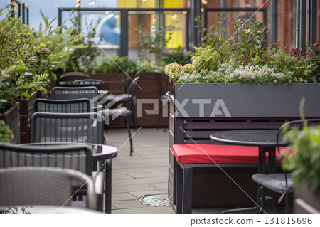 Modern european style empty street cafe with lovely natural flowers near tables in sunny day. Modern european style empty street cafe with lovely natural flowers near tables in sunny day. 131815696