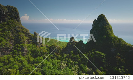 Aerial view majestic mountain cliffs covered in lush green rainforest hills slopes, overlooking pristine turquoise water lagoon, tropical ocean paradise. Popular travel destination, remote wild nature 131815743