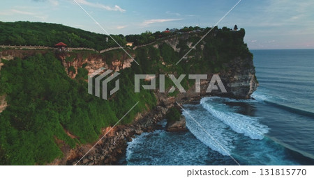 Aerial drone captures the breathtaking scenery of Pantai Dreamland Beach in Bali, Indonesia, with waves crashing against dramatic cliffs and lush green vegetation covering the landscape 131815770