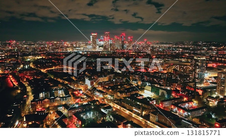 England, London: Canary Wharf and surrounding residential areas buildings skyscrapers glow with colorful lights at night, creating a stunning cityscape view from above, captured by a drone England, London: Canary Wharf and surrounding residential areas buildings skyscrapers glow with colorful lights at night, creating a stunning cityscape view from above, captured by a drone 131815771