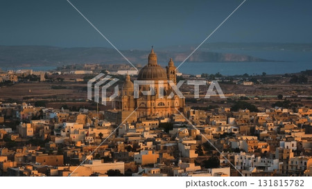Malta, Comino island: The Church of Saint John the Baptist, known as Xewkija Rotunda majestically rising in the heart of Gharb. Gozo. Village city basks in warm glow of sunset. Drone flight 131815782
