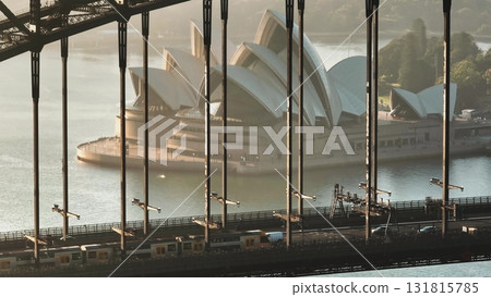 Australia, Sydney City: Framing Sydney Opera House with Sydney Harbour Bridge at sunrise. Train and cars driving traffic road, highlighting modern architecture and urban transport in Australia 131815785