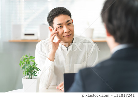 A middle-aged Asian male customer considering, worrying, thinking during a business meeting at a consultation desk A middle-aged Asian male customer considering, worrying, thinking during a business meeting at a consultation desk 131817241