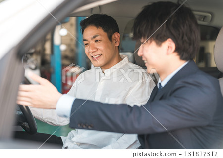 A male customer listening to a salesman's explanation inside a car at a showroom 131817312