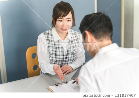 一名為顧客服務的女性接待員/職員和一名男性顧客 131817407