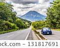 A blue car parked beside a long road leading to Mount Yotei. Autumn, October, Hokkaido 131817691