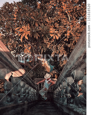 Woman descending steep stone stairs framed by dense orange foliage 131818520