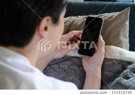 A man operating a smartphone in bed A man operating a smartphone in bed 131818799