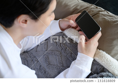 A man operating a smartphone in bed A man operating a smartphone in bed 131818809